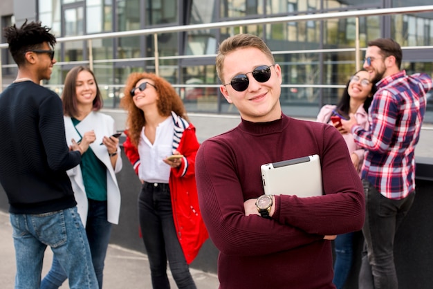 Portrait of happy young man carrying digital tablet looking at camera