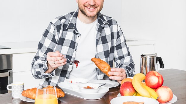 朝食でクロワッサンを食べて幸せな若い男の肖像