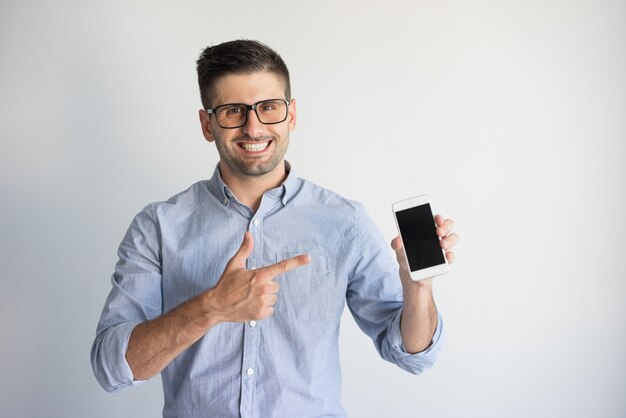 Portrait of happy young man in eyeglasses showing new smartphone.