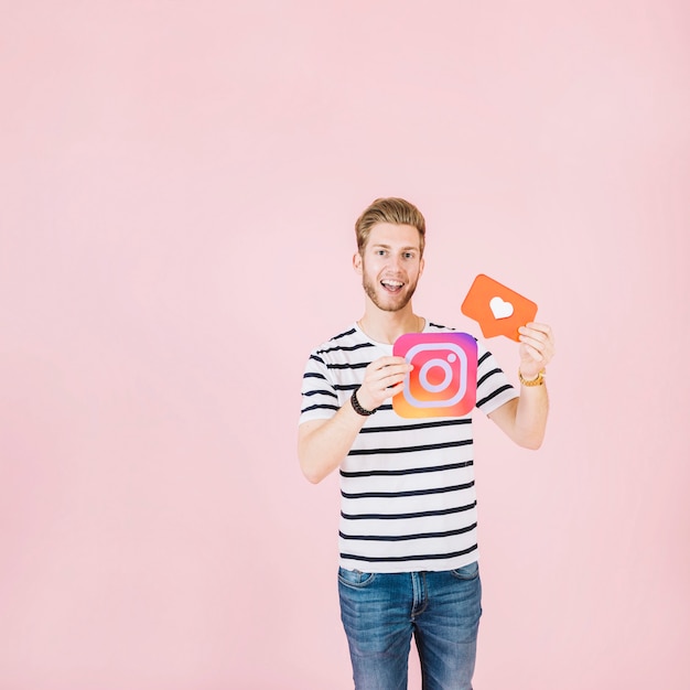 Free photo portrait of a happy young man holding instagram and like icon