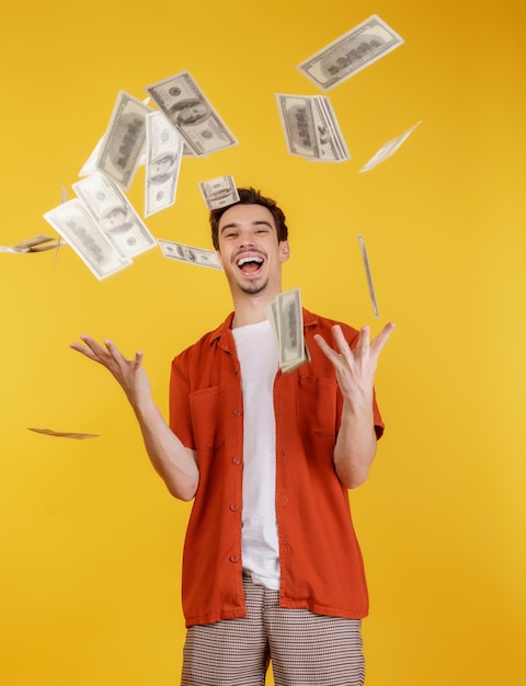 Portrait of happy young man throwing money up while standing isolated background