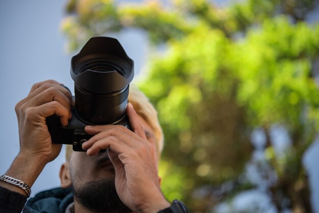 Portrait of happy young man, tourists with camera in mountain.