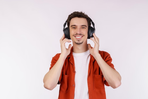 Ritratto di giovane uomo felice che indossa la cuffia e godetevi la musica su sfondo bianco