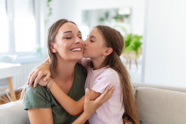 Portrait of happy young mother play hug and cuddle show love cute small preschooler daughter relaxing in living room smiling mom and little girl child rest enjoy family weekend at home together