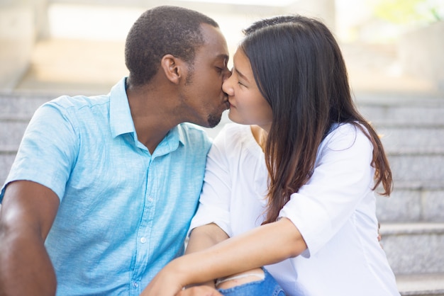 幸せな若い多民族カップルの階段にキスの肖像画。