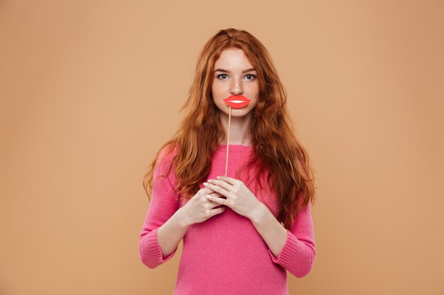 Портрет счастливой молодой рыжий девушка держит бумажные губы
