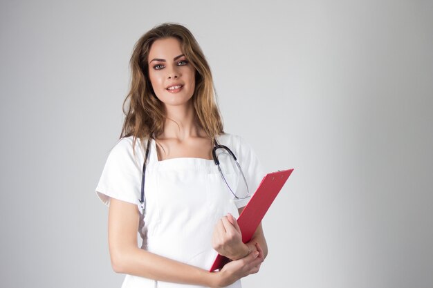 Portrait of happy young smiling female doctor holding a medical record clipboard.