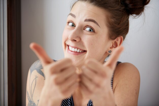 2つの親指のジェスチャーを与える幸せな若い成功した女性の肖像画