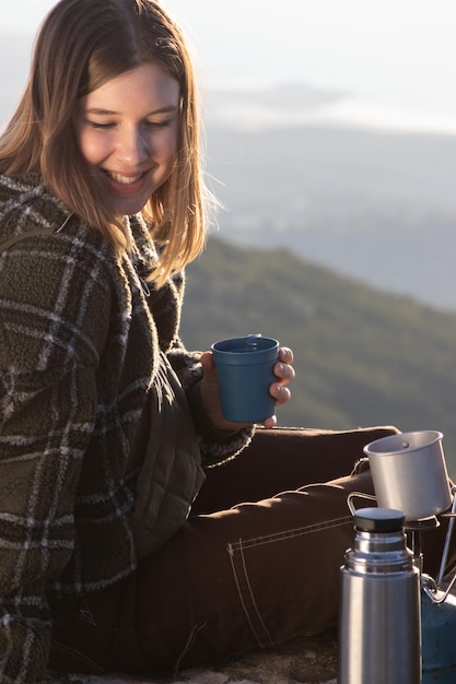 Free photo portrait of happy young woman drinking tea outdoors