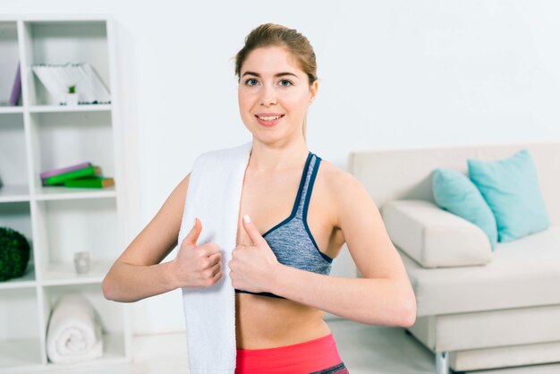 Портрет счастливой молодой женщины в одежды для фитнеса, показывая большой палец вверх знак