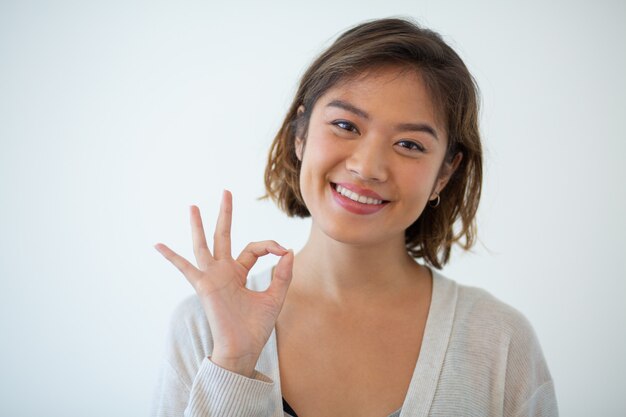 Portrait of happy young woman gesturing alright