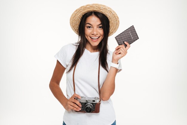 Portrait of a happy young woman in hat holding camera