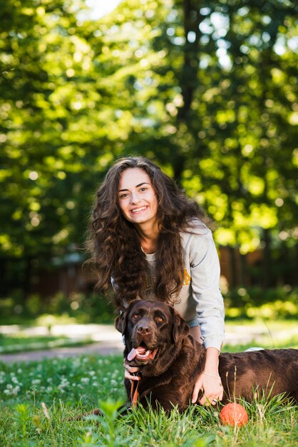 Портрет счастливой молодой женщины и ее собаки в саду