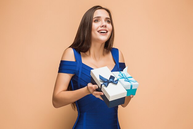 Portrait of happy young woman holding a gifts isolated on brown studio background