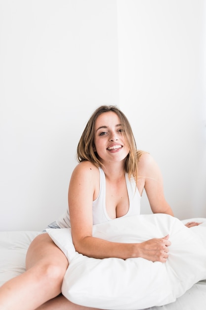 Foto gratuita ritratto di una giovane donna felice che si siede sul letto