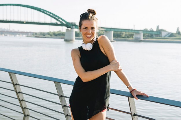 Portrait of a happy young woman standing in front of river