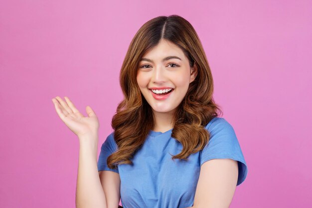 Portrait of happy young woman wearing casual tshirt waving hands isolated over pink background