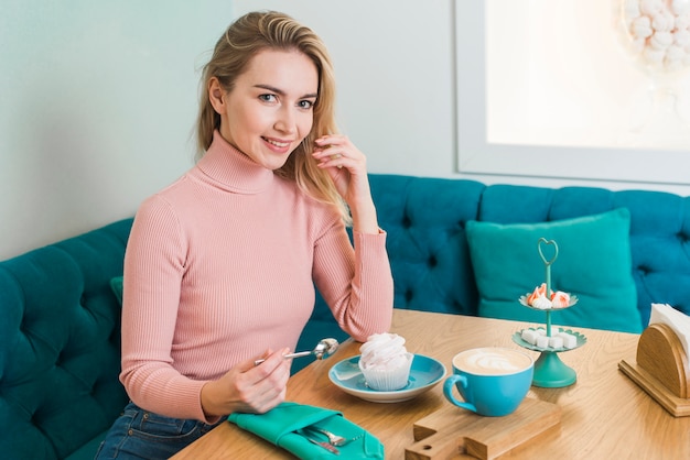 Portrait of a happy young woman with meringue and coffee