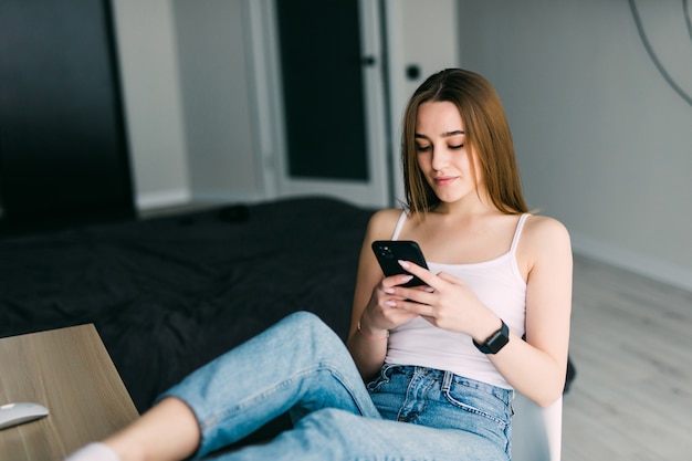 Portrait of happy young woman with mobile phone sitting on couch at home
