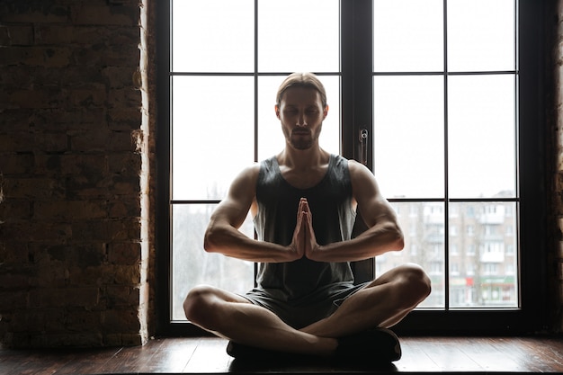 Free photo portrait of a healthy young sportsman meditating in lotus pose