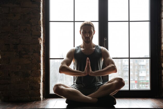 Portrait of a healthy young sportsman meditating in lotus pose