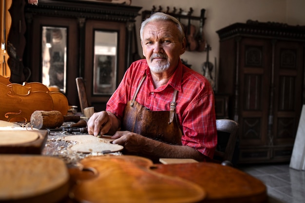 Free photo portrait of highly experienced senior craftsman in his carpentry workshop with tools working on his projects