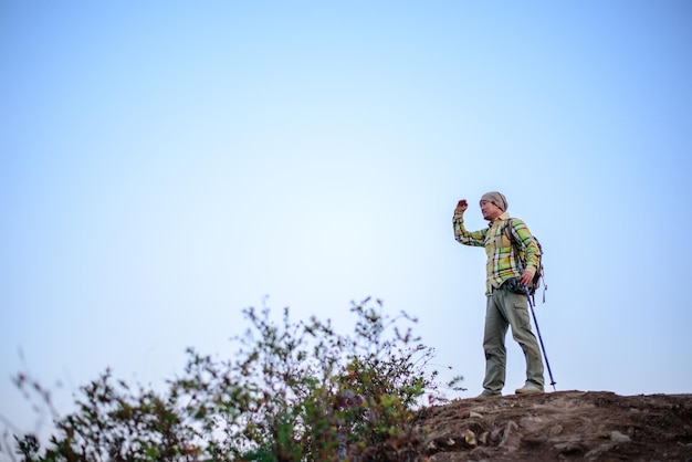 Ritratto di uomo escursionista in piedi sulla cima di una montagna o di una scogliera e guardando sulla valle con spazio di copia concetto di avventura vacanze estive all'aperto da solo in natura