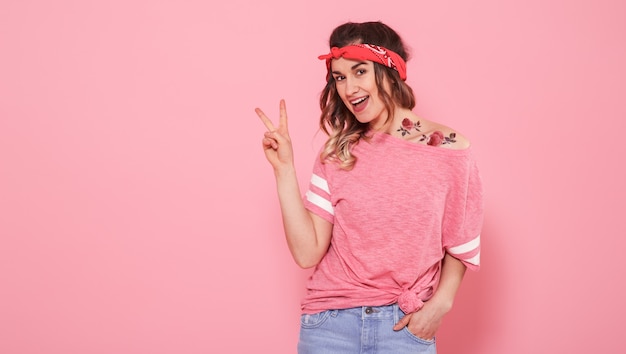 Portrait of a hipster girl with tattoo, isolated on pink wall