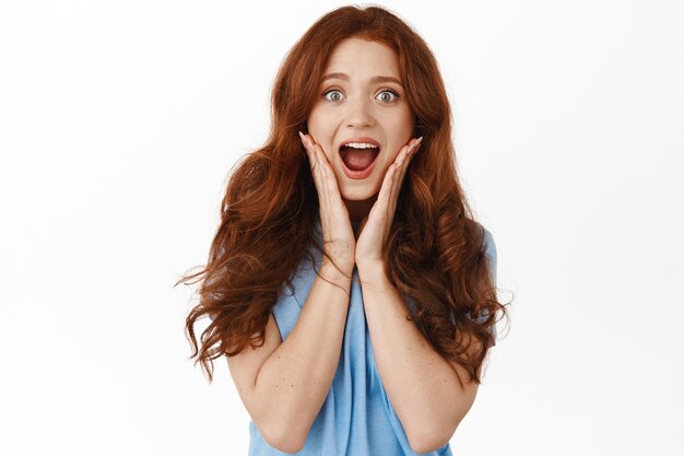 Portrait of impressed and excited redhead woman on white