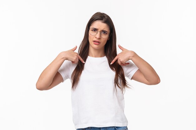 portrait of insulted, shocked and offended young frustrated woman pointing at herself