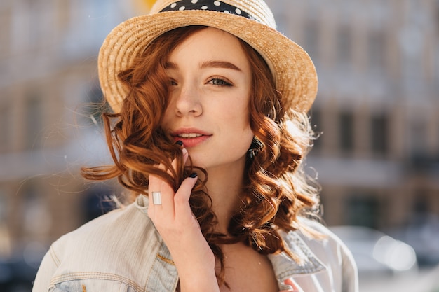 Foto gratuita ritratto della donna interessata dello zenzero che posa in cappello elegante. colpo esterno di splendido modello femminile con capelli ricci rossi, trascorrere il fine settimana in città.