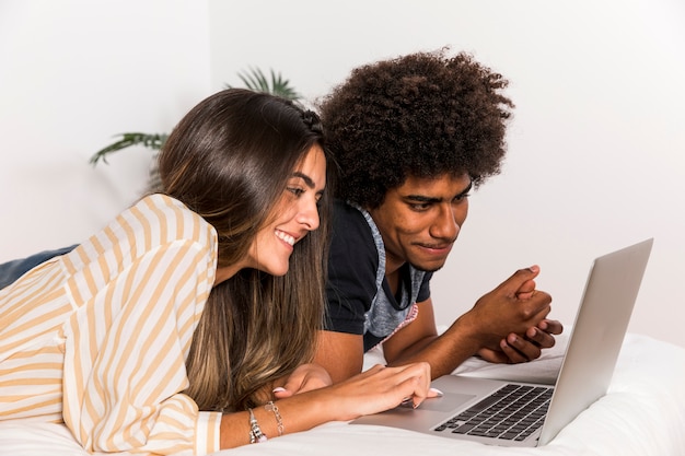 Ritratto delle coppie interrazziali facendo uso del computer portatile insieme