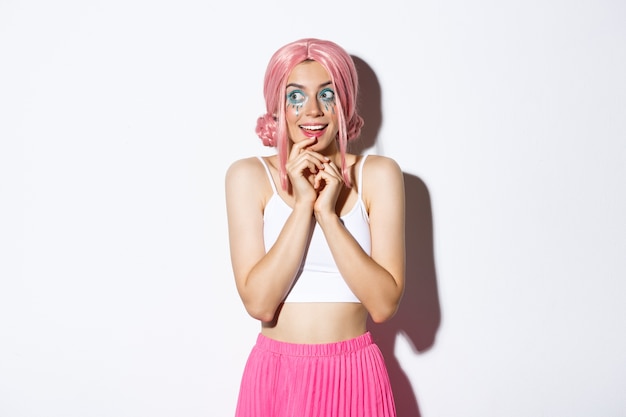 Портрет заинтригованной красивой девушки с розовым париком и ярким макияжем, смотрящей налево на что-то соблазнительное