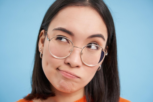 Foto gratuita il ritratto della donna giapponese con gli occhiali sembra pensieroso riflette pensando con la faccia seria in piedi o