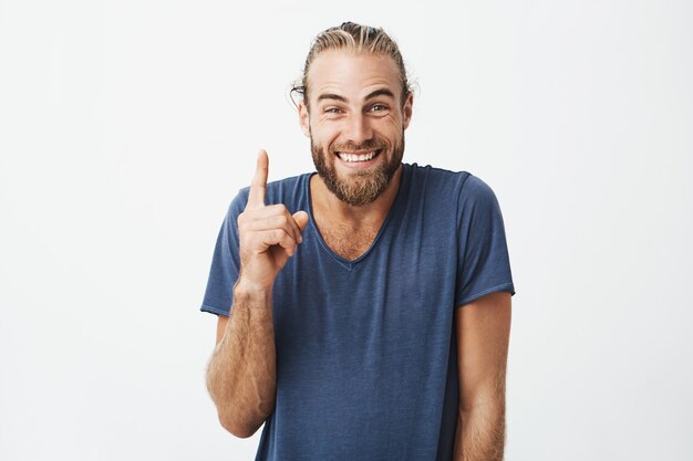 Portrait of joyful beautiful men with fashionable hairstyle and beard, pointing up