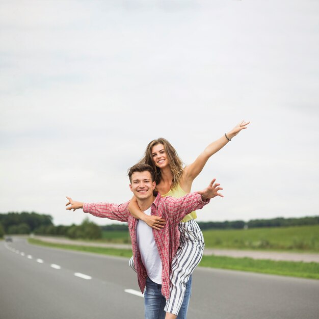 Free photo portrait of a joyful man carrying her girlfriend on his back and having fun