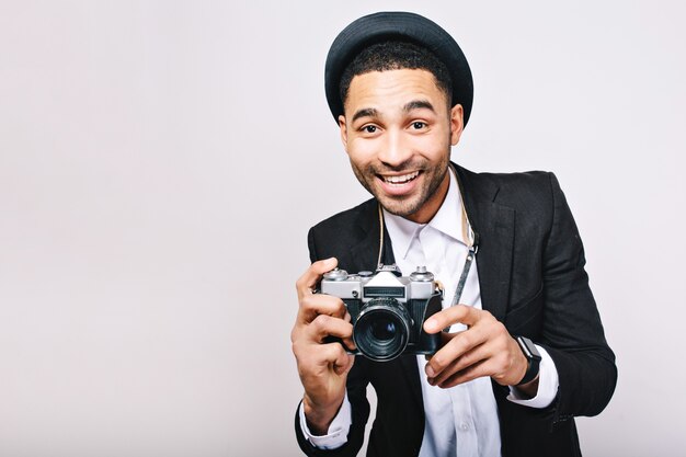 Портрет радостного успешного парня в костюме, шляпе, весело проводящей время с камерой. Счастливый турист, фотограф, стильный взгляд, путешествующий, улыбающийся, взволнованный, изолированный.