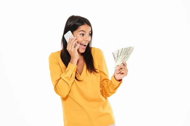 Portrait of a joyful surprised woman talking on mobile phone