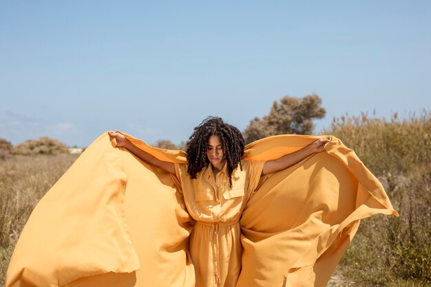 Portrait of joyful woman with yellow cloth in nature