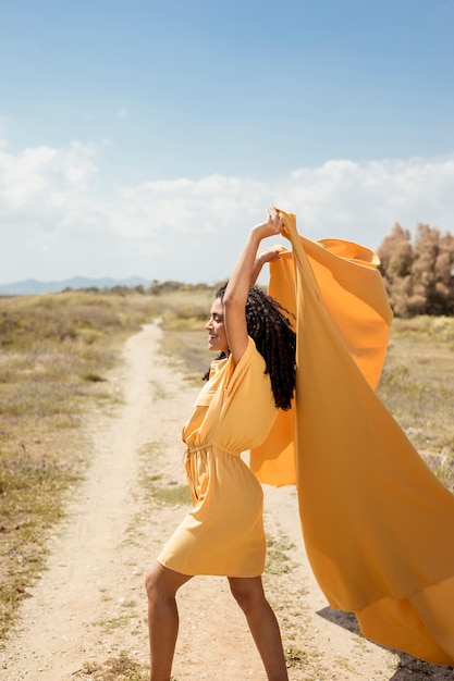 Foto gratuita ritratto di donna gioiosa con un panno giallo in natura