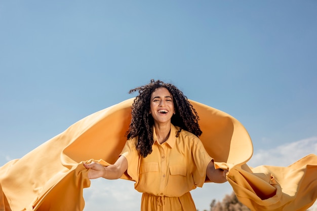 Foto gratuita ritratto di donna gioiosa con un panno giallo in natura