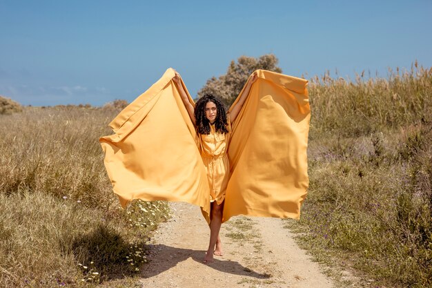 Portrait of joyful woman with yellow cloth in nature