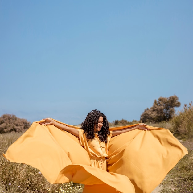 Portrait of joyful woman with yellow cloth in nature