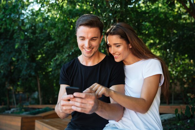 Portrait of a joyful young couple looking at mobile phone