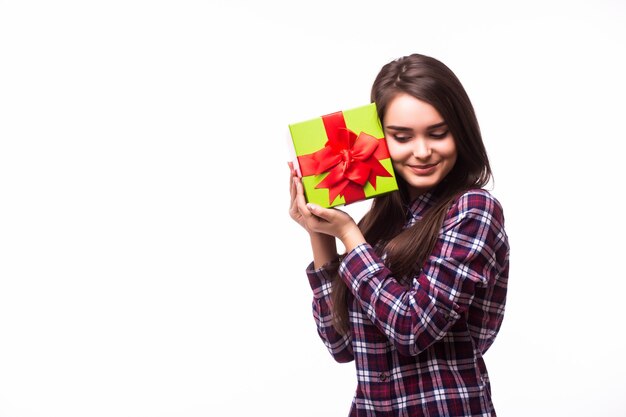 Portrait of a joyful young woman dressed in red dress holding stack of gift boxes and celebrating isolated over white background