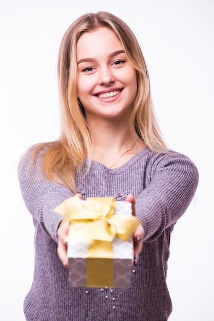 Ritratto di una giovane donna allegra vestita in vestito rosso che tiene pila di scatole regalo e celebra isolato sopra il muro bianco