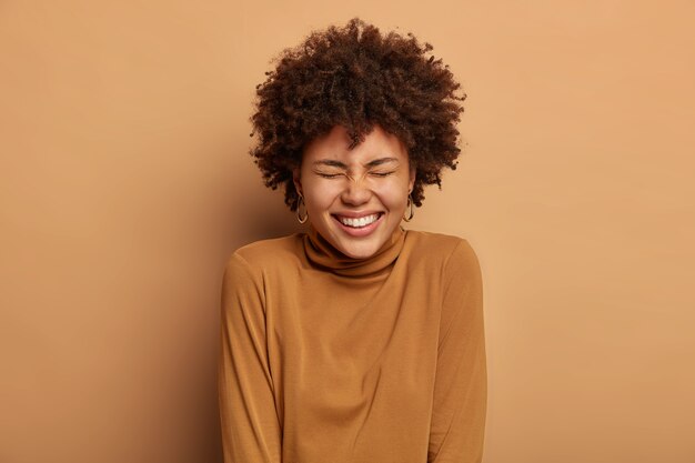 Portrait of joyous glad lady with toothy smile, laughs out as hears comic story, being in high spirit, enjoys happy day