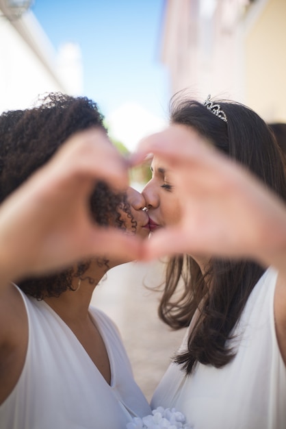 Foto gratuita ritratto di donne appena sposate che fanno il segno del cuore