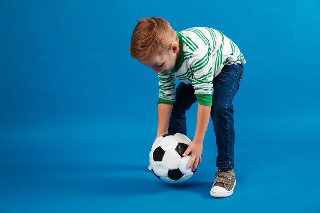 Портрет ребенка собирается пнуть футбольный мяч