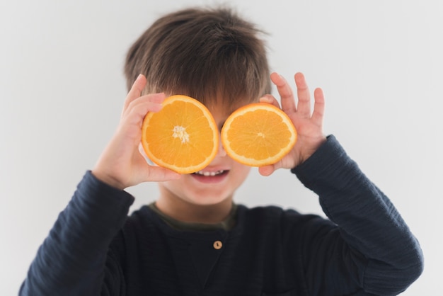 目の上のオレンジ色の半分を保持している子供の肖像画